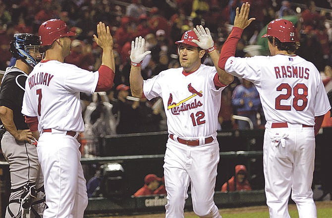 St. Louis Cardinals' Lance Berkman (12) celebrates with teammates Matt Holliday (7) and Colby Rasmus (28), as Florida Marlins catcher John Buck looks on in the third  inning of a baseball game, Monday, May 2, 2011 in St. Louis.