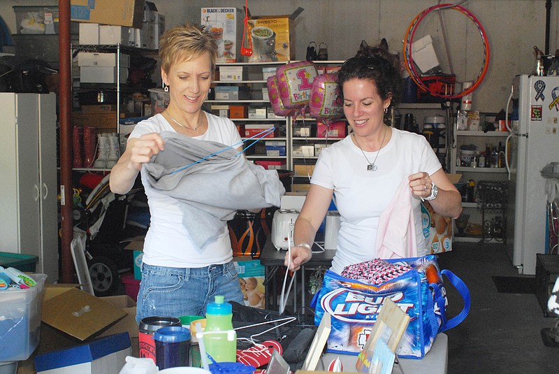 Gloria Hansen, left, and D'Arcy Crane hang up clothing items in preparation for a neighborhood rummage sale this weekend. 
