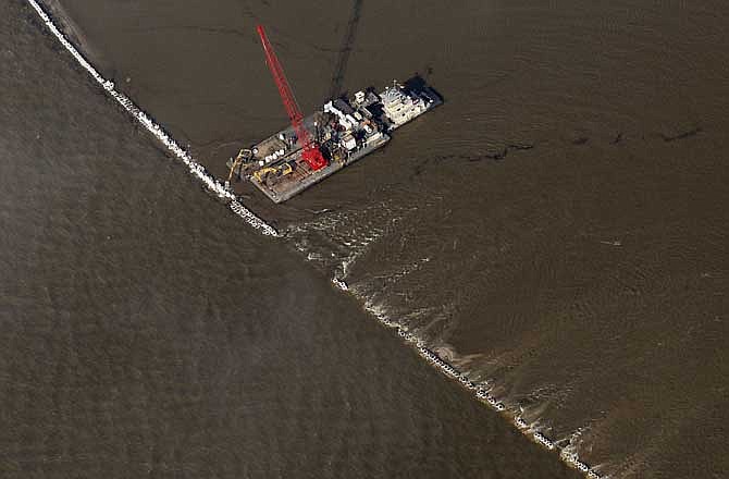 Workers use a barge to fix an overtopped levee in a basin near the Morganza Spillway in Morganza, La., Saturday, May 14, 2011. Officials opened a bay on the spillway structure to alleviate pressure on local levees.