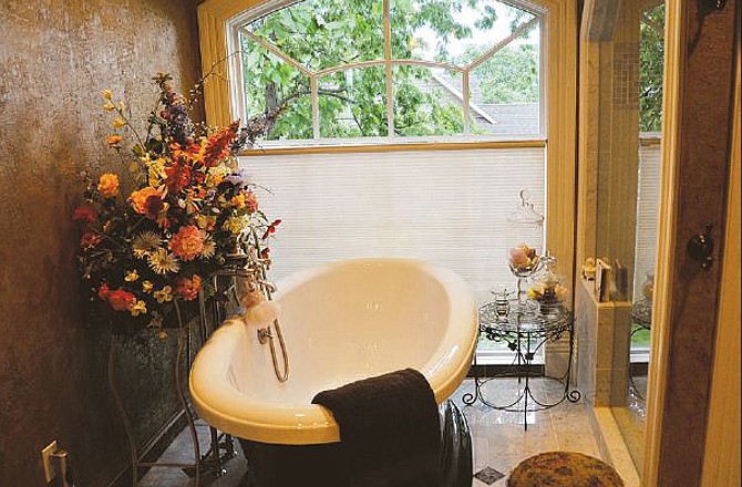 Ann Littlefield's master bathroom has lots of windows and glass. Clear jars hold soap near the tub. 