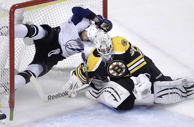 Boston Bruins goalie Tim Thomas, right, makes a save as Tampa Bay Lightning center Steven Stamkos ends up airborne as he is checked into the goal during the first period of Game 5 of the NHL hockey Stanley Cup playoffs Eastern Conference finals, in Boston on Monday, May 23, 2011.