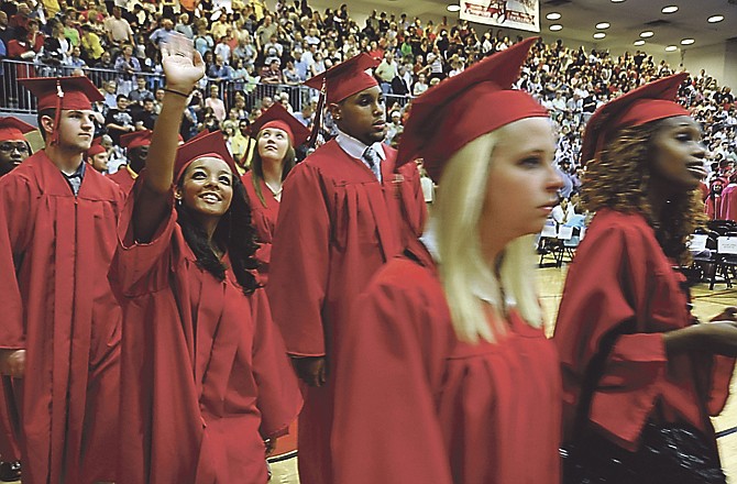 Kymber Walker waves to a spectator as she and other 2011 graduates enter the gym Sunday evening at Jefferson City High School. This was the 137th commencement with 622 students, the largest graduating class in the school's history. Bad weather forced the event inside Fleming Field House.