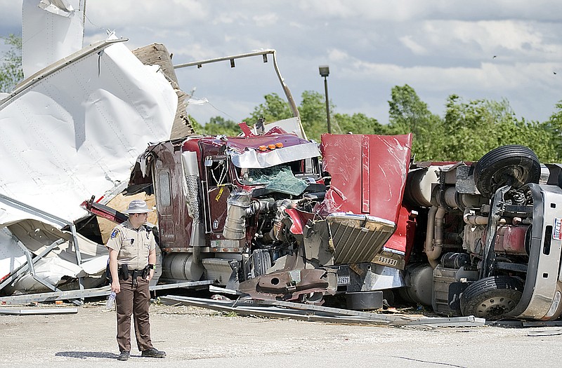 Pettis County Sheriff's Deputy Wes Burton stands guard Wednesday behind a truck stop in Sedalia to prevent people from entering a trailer park that was off-limits to the public because of gas leaks and downed power lines from a tornado strike. 