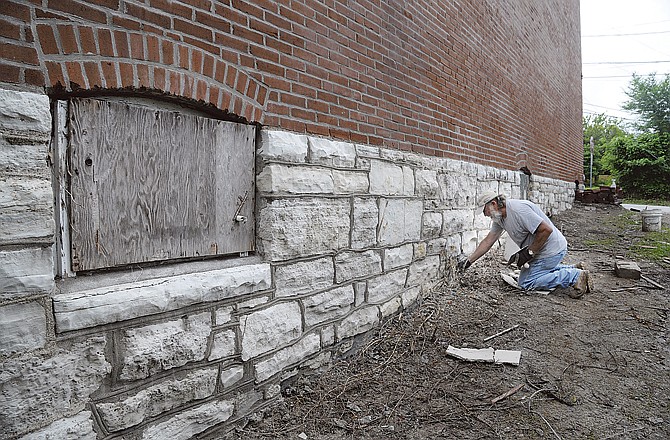 Larry Hoffman of James A. Staat Tuckpointing applies mortar to the joints on the foundation of the building at the corner of East Atchison Street and Clark Avenue.
