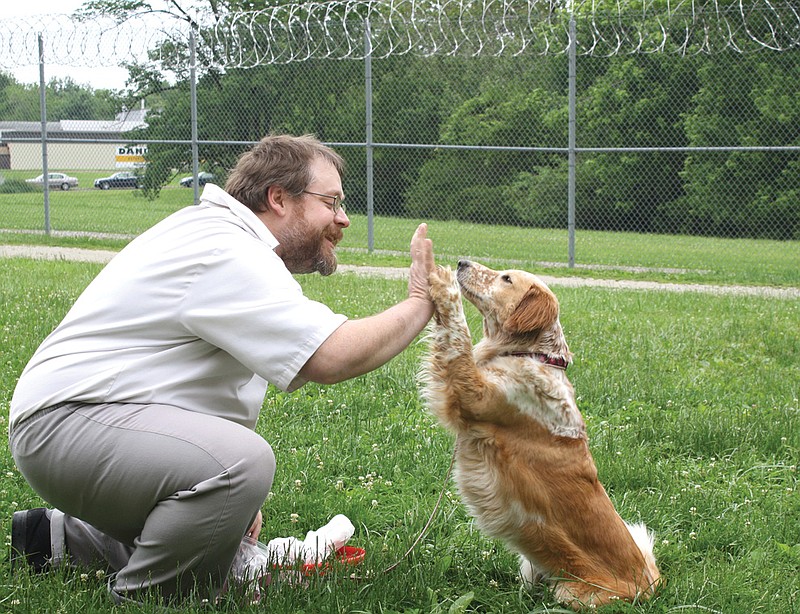 Ceree gives her handler, Joseph Zelk, a high-five on Thursday at Cremer Therapeutic Community Center. Ceree recently came to the center as a therapeutic house dog for the offenders.