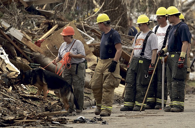 Kim Stuart, from Little River, Ark., and her dog Thunder along with other searchers look for bodies in a devastated Joplin, Mo. neighborhood Saturday, May 28, 2011. An EF-5 tornado tore through much of the city last Sunday, damaging a hospital and hundreds of homes and businesses and killing at least 139 people.