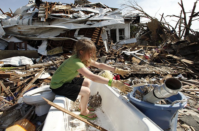 Laura Cobb, 11, cleans debris from a bathtub while helping with cleanup at her destroyed home in Joplin.