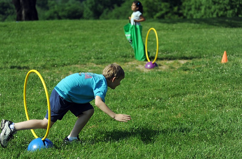 Graham Yerian, 7, left, runs through a hoop as Rani Patel, 8, hops in a sack during a team obstacle course race Tuesday at a Youth Sports Day Camp presented by the Parks and Recreation Department.