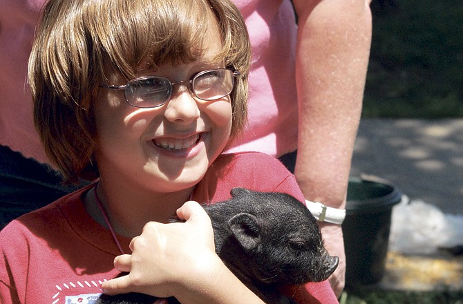 
Meara Perkins grins from ear to ear while she holds a little piglet brought to last year's KidsFest in Jefferson City. 