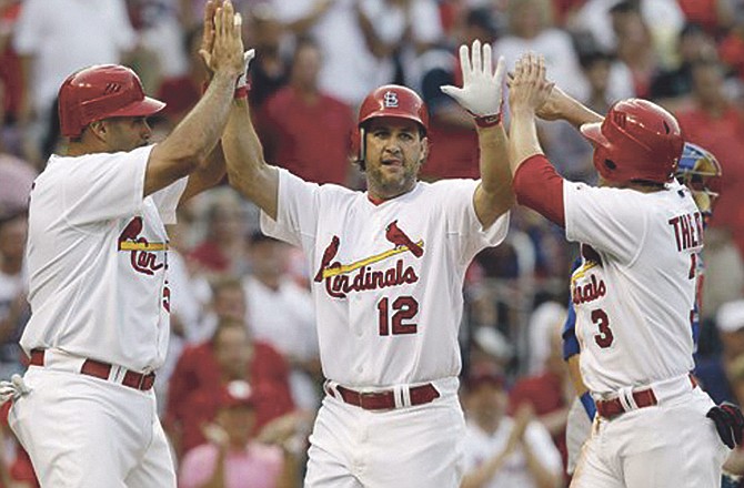 St. Louis Cardinals' Lance Berkman, center, is congratulated by teammates Albert Pujols, left, and Ryan Theriot after hitting a three-run home run during the first inning of a baseball game against the Chicago Cubs Friday, June 3, 2011, in St. Louis.