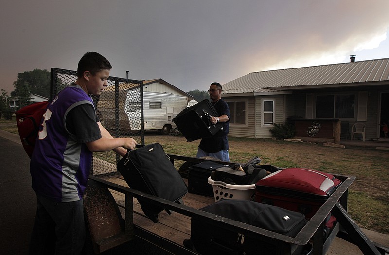 Vincent Chavez, left, and his father, Cody, gather their belongings Tuesday as they prepare to evacuate their home in Springerville, Ariz. Firefighters spent the day working feverishly to prepare a defense for Springerville and nearby Eagar as a raging forest fire approached. 