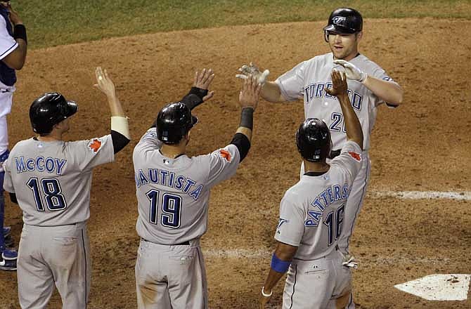 Toronto Blue Jays' Adam Lind (26) celebrates with teammates Mike McCoy (18), Jose Bautista (19) and Corey Patterson (16) after hitting a grand slam during the fifth inning of a baseball game against the Kansas City Royals, Wednesday, June 8, 2011, in Kansas City, Mo. 
