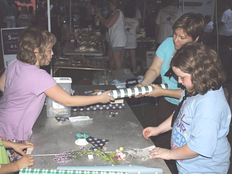 Becca Noel (right); Tammy Gillespie (center) and Kelly Gillespie (right) make craft hats at their booth during the Callaway County Relay for Life event at McClure Field on Friday.