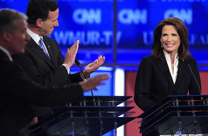 Rep. Michele Bachmann, R-Minn., answers a question as former Pennsylvania Sen. Rick Santorum, center, applauds while CNN's John King, left looks on during the first New Hampshire Republican presidential debate at St. Anselm College in Manchester, N.H., Monday, June 13, 2011. Bachmann, invited as an unannounced contender for the 2012 nomination, used the debate to announce she had filed papers earlier in the day to run. (AP Photo/Jim Cole)