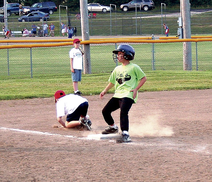Kaleb Keeran, Cal's 2, makes it to third base after escaping a hot-box at the CRA Intermediate Boys' ball game June 7. At left is American Family third baseman Jesse Wingate, retrieving the ball.