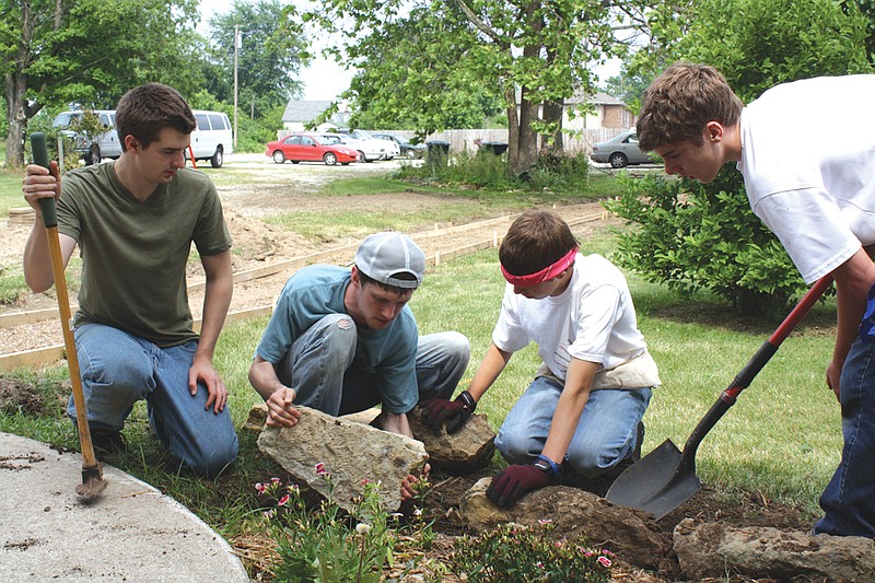 (From left) Eric Banta, 18, Andrew Winslow, 20, Joshua Vita, 14, and Evan Todd, 16, work together on a landscaping job Tuesday.