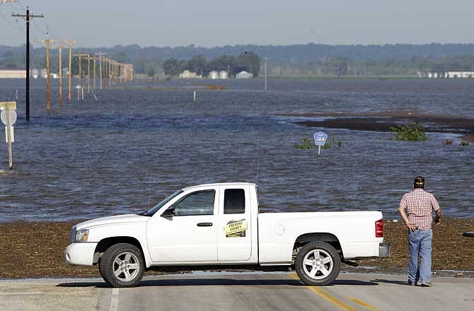 An official checks the water level as floodwaters from the nearby Missouri River cover a county highway, Wednesday, June 15, 2011, in Hamburg, Iowa. The water level continues to rise and officials say that it should crest sometime later this week.