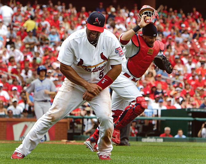St. Louis Cardinals first baseman Albert Pujols, left, grabs his left wrist after being injured on a play at first base as catcher Yadier Molina, right, chases a lose ball during the sixth inning of an interleague baseball game against the Kansas City Royals Sunday, June 19, 2011, in St. Louis. Pujols left the game (AP Photo/Jeff Roberson)