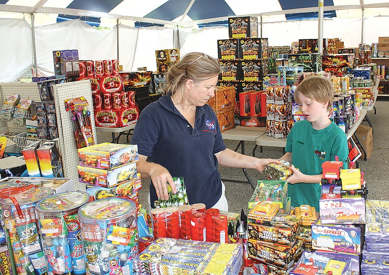 Susan Peterson and her son, Caleb, sort through fireworks at the Cosmo Fireworks stand located on South Business 54 in Fulton. The stand is now open and selling fireworks with part of its proceeds going to benefit Kingdom Christian Academy.
