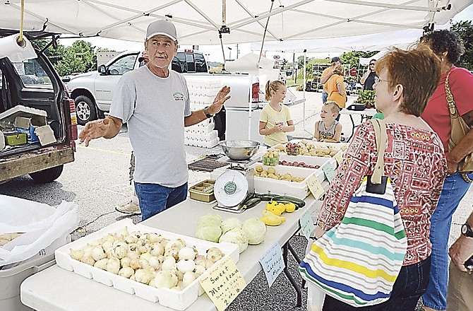 James Hohman of Home-N-Grown produce, near Russellville, and his granddaughter, Elliott Hull, sell onions, cabbage, squash and several types of potatoes during the Cole County Farmers Market on the Kmart parking lot in Jefferson City. 