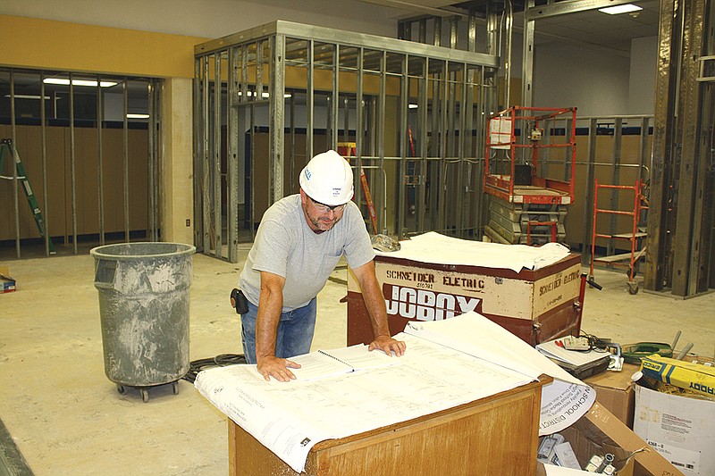 Steve Werder, carpenter with Glove Con, Inc., looks over remodel plans of the Fulton High School Library and Media Center Monday as work continues on the project.