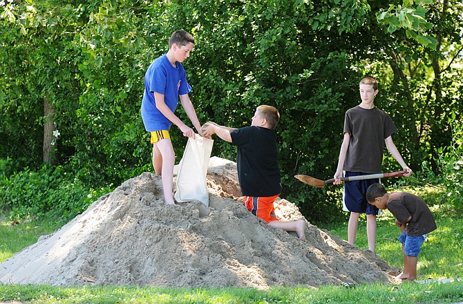 Jimmie Wehmeyer, left, and his twin brother, Charlie, at right with shovel, along with their cousins Tristan, kneeling, and Elijah Brocksmith, fill sandbags as they prepare for the impending rising water, which may reach the Wehmeyer home's foundation.