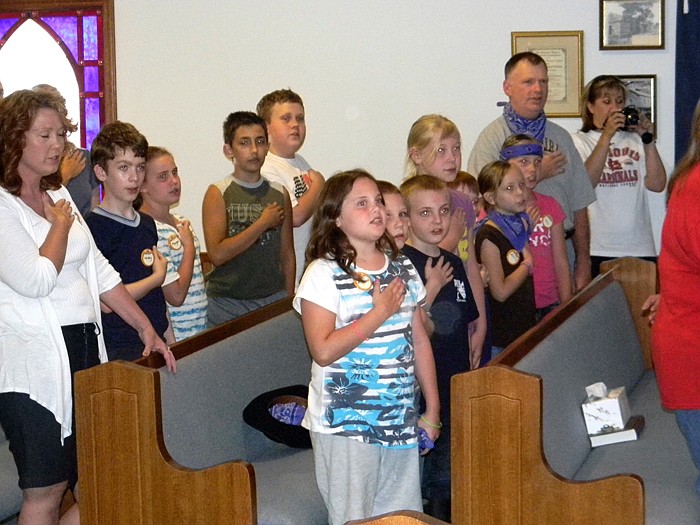 Children and adults recite the Pledge of Allegiance to the American Flag.
