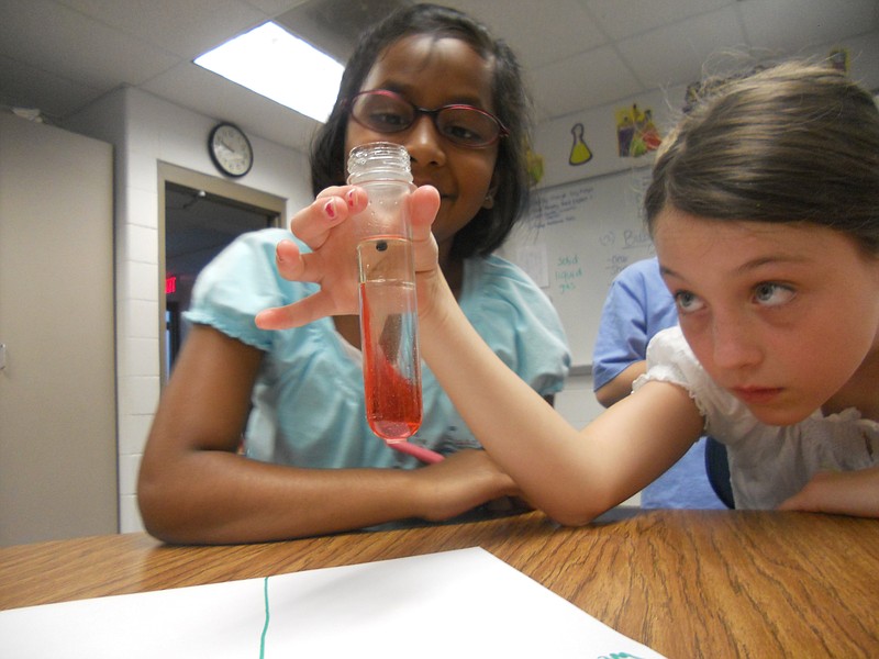 Sudhi Kumar and Molly Quick demonstrating different levels of density in a "Cauldron Bubbles" experiment at Camp TLC.