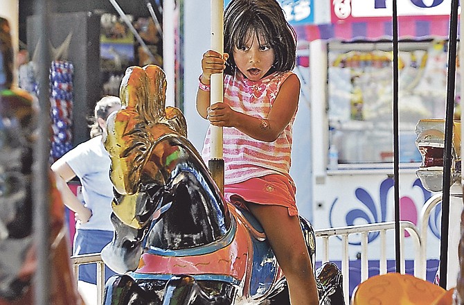 A 5-year-old girl rides the carousel Saturday at the carnival set up on Capitol Avenue in downtown Jefferson City for the Salute to America.