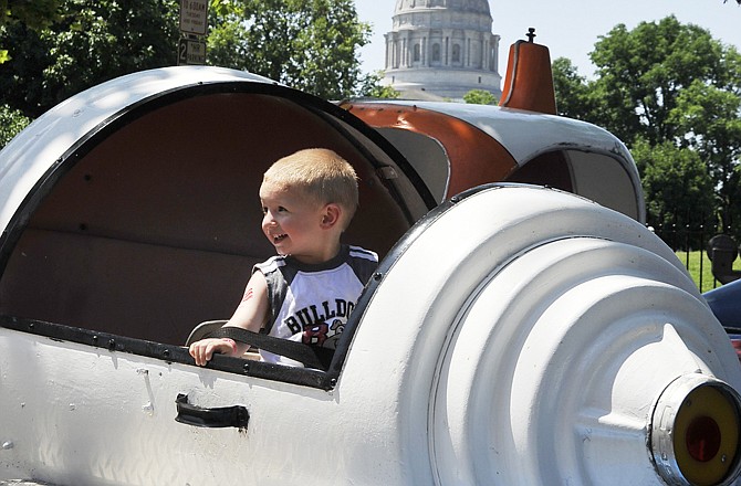 With Missouri's Capitol as a backdrop, Colton Nitschke enjoys a ride in a spacecraft Saturday at the carnival along Capitol Avenue during Jefferson City's Salute to America.
