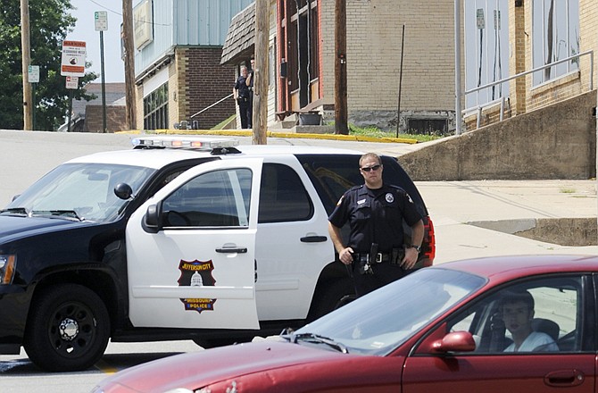 A police officer directs traffic away from The Mission, buff building center right in background, near the intersection of Ash and High streets. A man inside the building surrendered a few minutes later Monday afternoon.