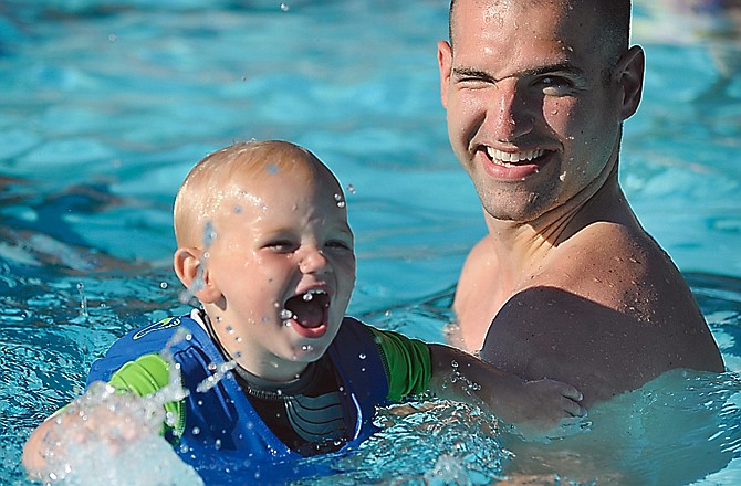 Nolan Maasen, 17 months, laughs and splashes with his dad, Cameron Maasen, during the Parent and Child Aquatics class at the Ellis Porter Park in Riverside Park.