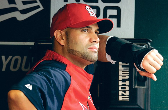 Albert Pujols stands in the Cardinals' dugout with a soft cast on his left arm during a game last month at Busch Stadium. Pujols could be back in the Cardinals' lineup tonight against the Reds.