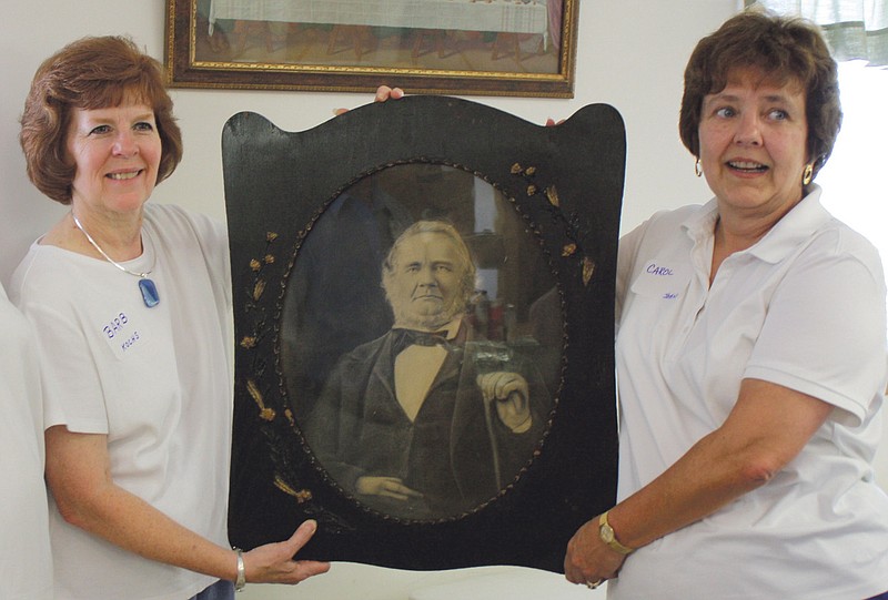 Barb Huddleston, left, curator for the Callaway County Historical Society, accepts a portrait of Joseph Scholl II, a Callaway County pioneer and grandson of Daniel Boone, from Carol Trumbold, a great grandchild of Scholl. The presentation came Saturday during a Scholl family reunion in New Bloomfield attended by about 70 people from throughout the United States. 