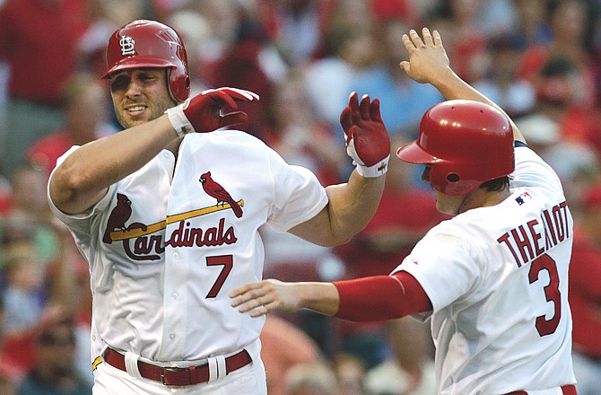 Matt Holliday (7) of the Cardinals is congratulated by Ryan Theriot after hitting his second home run during the fifth inning of Tuesday's game against the Reds in St. Louis.