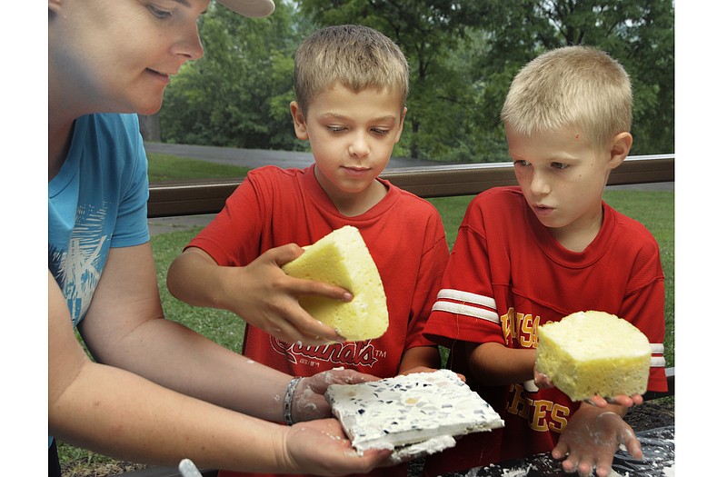 Lisa Allee holds a tile board while Mathias Roberts, middle, and Chase Dietzel wipe off the excess grout. Allee is one of the organizers of the Adventures in Science camp put on by the Jefferson City Parks, Recreation and Forestry Department. 