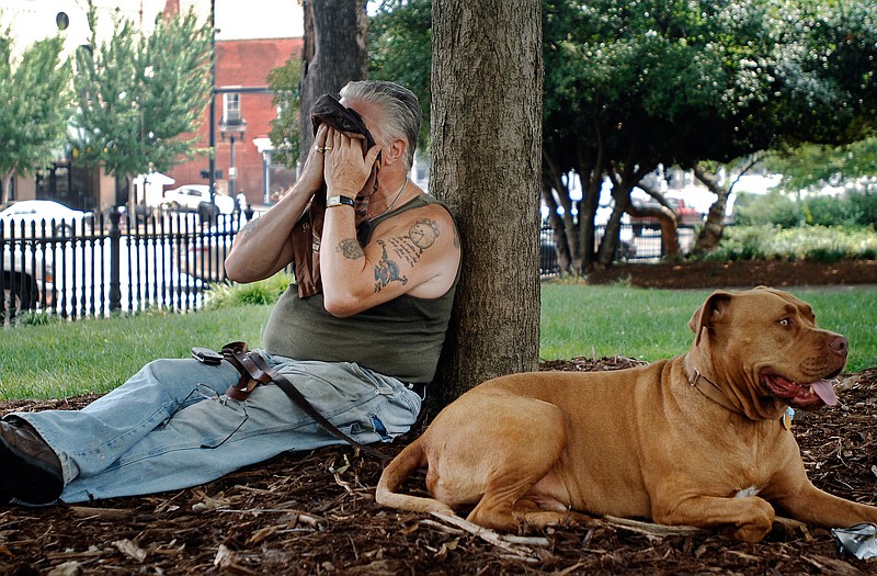 Retired Danielsville, Ga., resident Frank Milo cools down Monday under the shade of a tree on the University of Georgia's North Campus along with his dog, Milo, in Athens, Ga. Areas of the South and Midwest are facing lingering sweltering temperatures this week and possibly into next week.