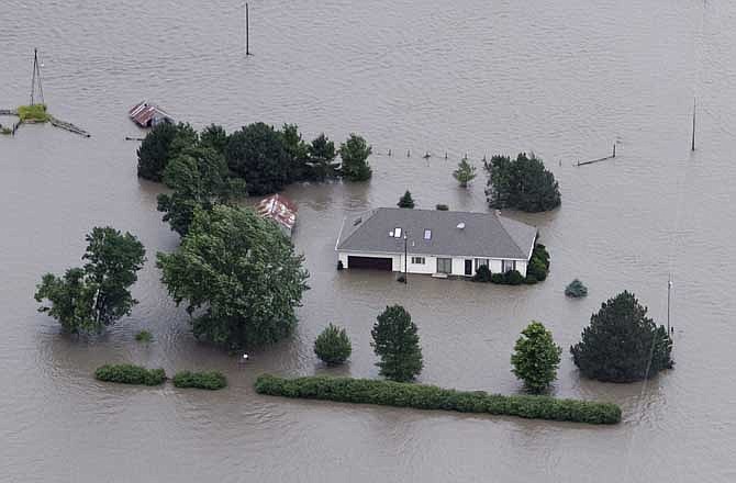 In this June 13, 2011 file photo, a home is engulfed by flood water in Hamburg, Iowa, from the rising Missouri River. Insurance agents in states along the swollen Missouri River basin say federal officials are causing widespread confusion among property owners by pushing the sale of flood insurance policies that might not cover damage from the river flooding.