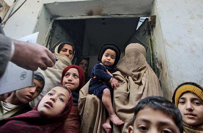 In this Dec. 28, 2010 file photo, a Pakistani health worker, left, visits families to inform them on polio in Peshawar, Pakistan. Pakistani officials and international health organizations expressed concern Wednesday July 13 2011, that reports of a phony CIA vaccination program meant to obtain DNA evidence that Osama bin Laden was hiding in a Pakistani town could harm legitimate immunization programs in the country. 