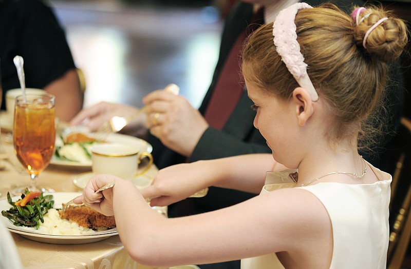 Hanna Lenz, 8, of St. Louis, uses a knife and fork to cut her chicken during a formal luncheon Wednesday at the Missouri Governor's Mansion. She attended a manners course hosted by the Missouri Mansion Preservation Foundation. 