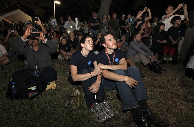 Johnson Space Center employees Jeremy Rea, right, and Shelley Stortz hold hands as they watch space shuttle Atlantis land Thursday in Houston.