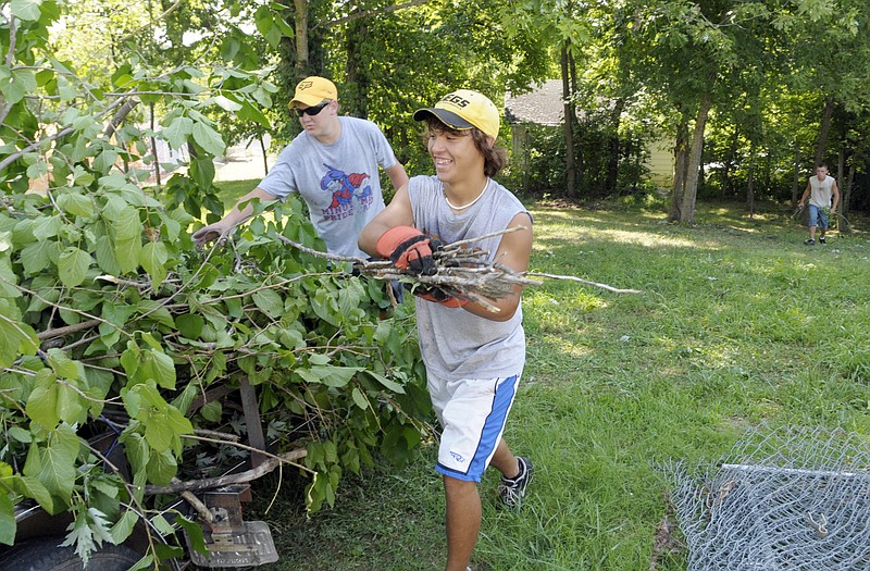 
Jeremiah Stewart, right, and Garrett Sanders pick up branches on a trailer while their teammate, TJ Whitworth, rear, does the same. They are volunteers from around the state who are with the Mid-Missouri Mission Team. Teens have converged on Jefferson City this week to help out at different locations where their help was requested.