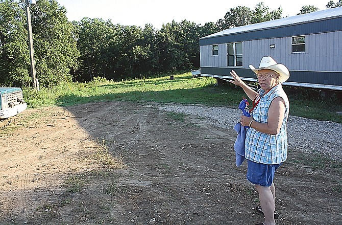 Betty Curtis gestures to the area she and her husband plan to clear to make room for additional mobile homes or campers to house more women.
