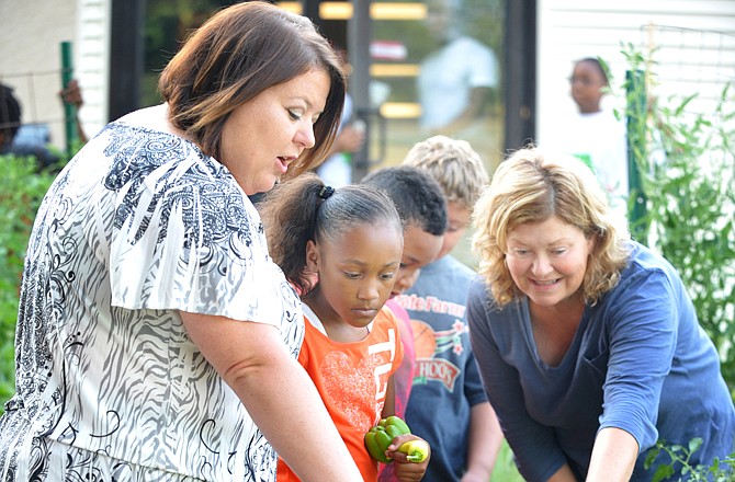 Stephanie Johnson, left, stands in the garden adjacent to the Boys and Girls Club of Jefferson City with Master Gardener Dana Calcutt, at right, looking at the successful planting. Next to Stephanie is Thojuree Johnson and Marcus Robinson, both attendees and gardeners. Today is Johnson's 100th day as executive director of the club, which has children working with area Master Gardeners to grow food.