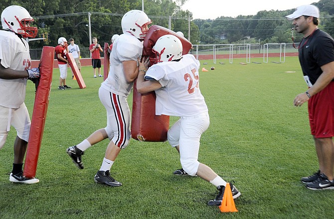 Jefferson City assistant coach Kevin Steinmetz (right) oversees players running a linebacker stun drill during the Jays football camp Thursday evening at Adkins Stadium.