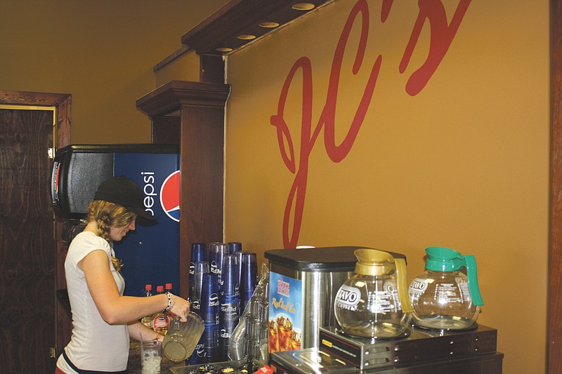 Rebecca Revak, server at JC's Restaurant, pours a glass of water for a customer. JC's Restaurant opened its doors Monday.