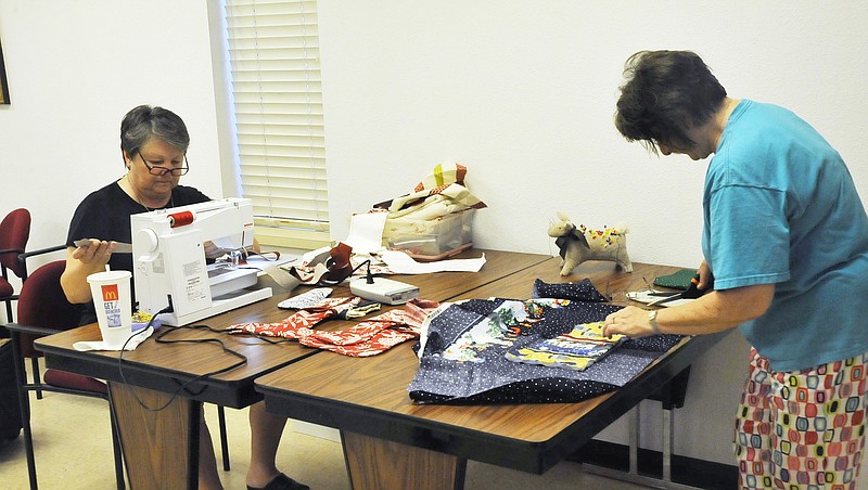 Janet Mehmert, left, sews as Bobbie Uballez cuts out a pattern for Christmas Stockings at the Missouri River Quilt Guild's workday on Saturday at the Coca-Cola room. The stockings will be given to area food banks for fund raising efforts this fall. 