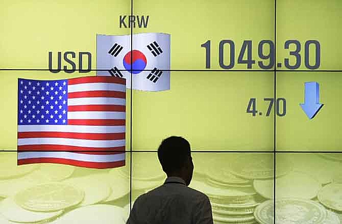 A man walks past a screen showing the exchange rate between the U.S. dollar and the South Korean won in Seoul, South Korea, Monday, Aug. 1, 2011. South Korean stocks rose 39.1 points, or 1.83 percent , to close at 2,172.31, Monday as foreign investors scooped up blue-chip auto and tech exporters on hopes that the U.S. Congress would approve the U.S. debt limit increase. 