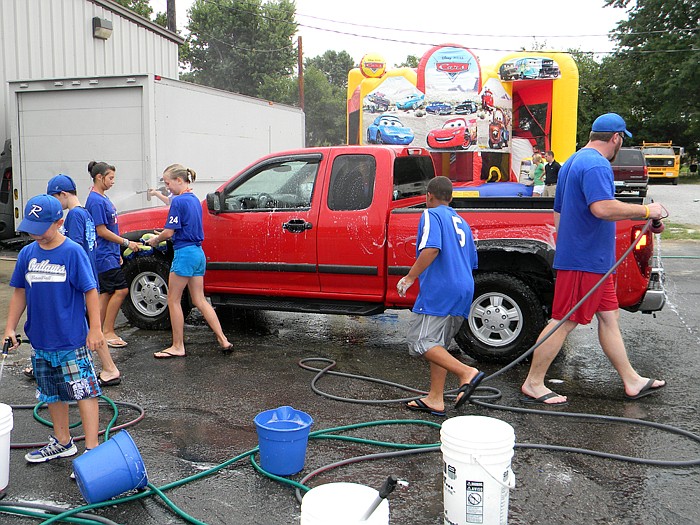 Jordon Geiser's Russellville Outlaws teammates and family wash cars at the Geiser family fundraiser held Saturday, July 30, at Fischer's 2 Bodyshop.