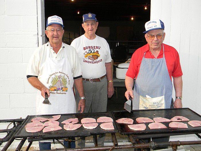 Kiwanis Club members Eddie Blankenship, left, Bob Keil, middle, and Richard Barry, cook the ham at the Kiwanis Club Ham Breakfast held Saturday, July 30, at Centennial Hall.